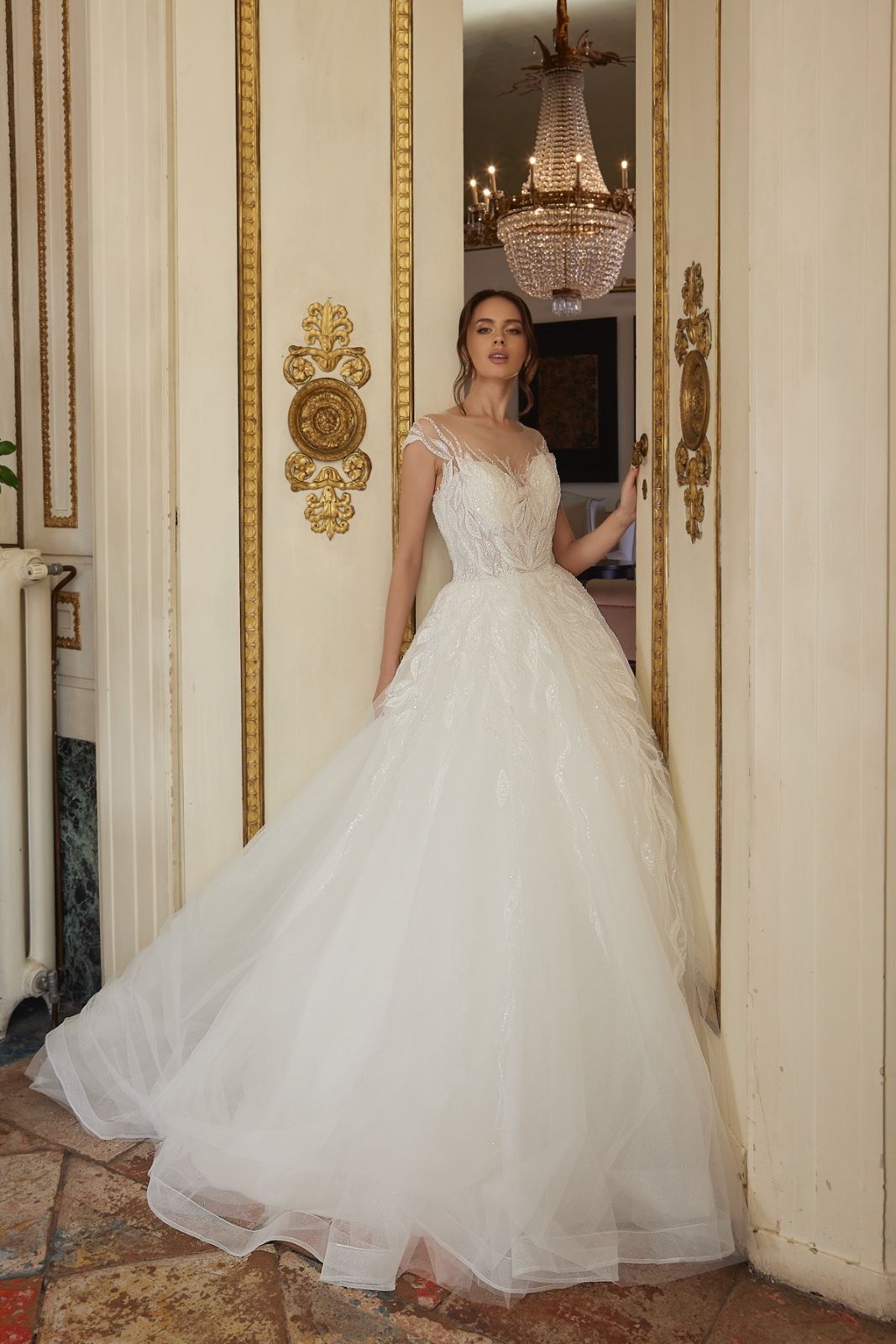 Una donna in abito da sposa bianco è in piedi sulla porta.