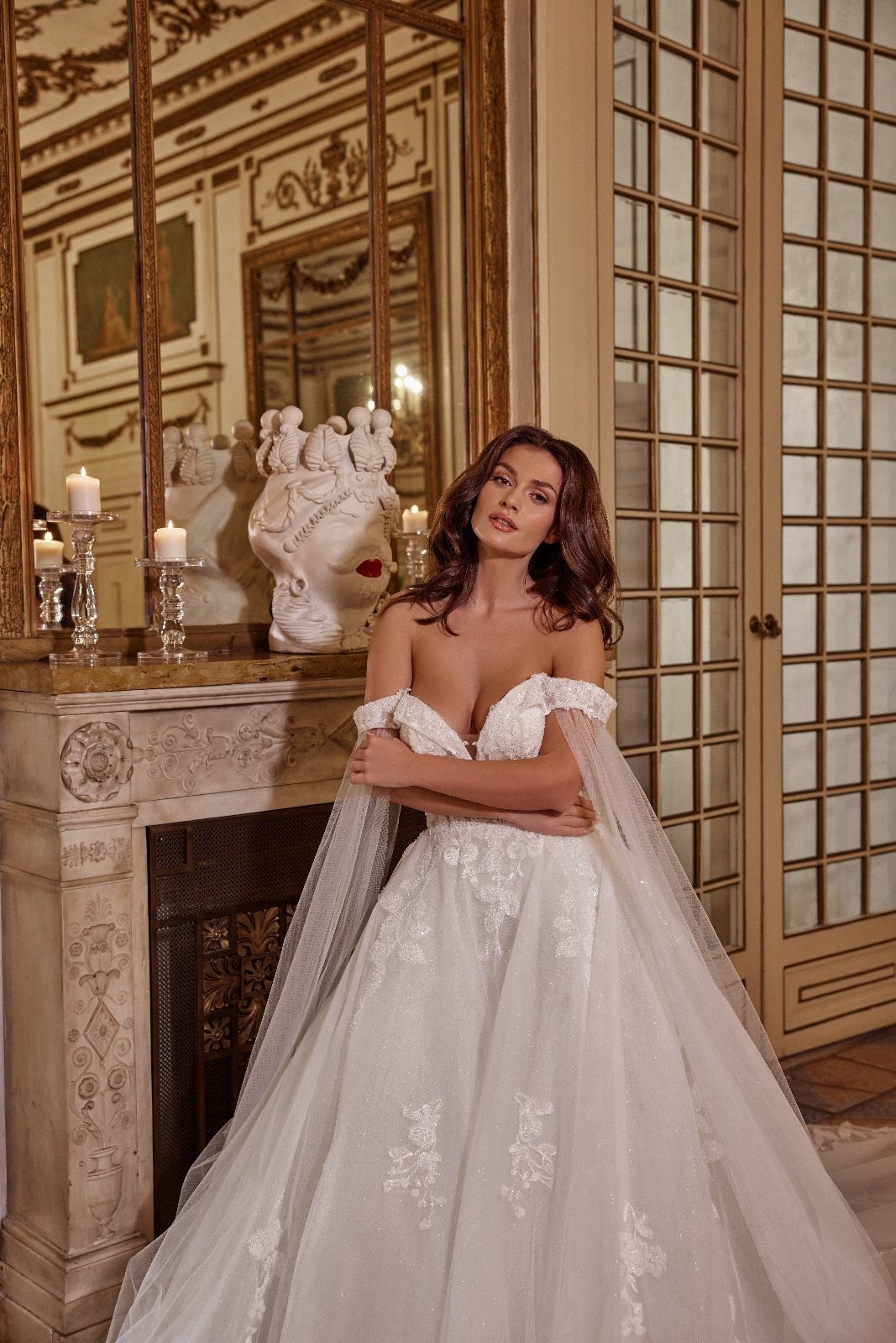 Una donna in abito da sposa è in piedi davanti a un camino.