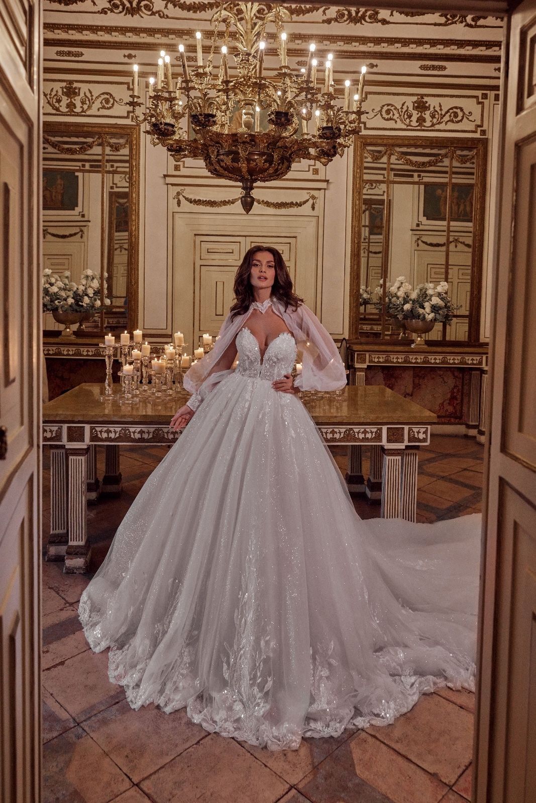 Una donna in abito da sposa è in piedi in una stanza accanto a un tavolo.