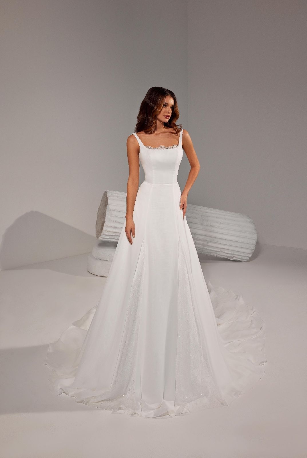 Una donna in abito da sposa bianco è in piedi davanti a un pilastro bianco.