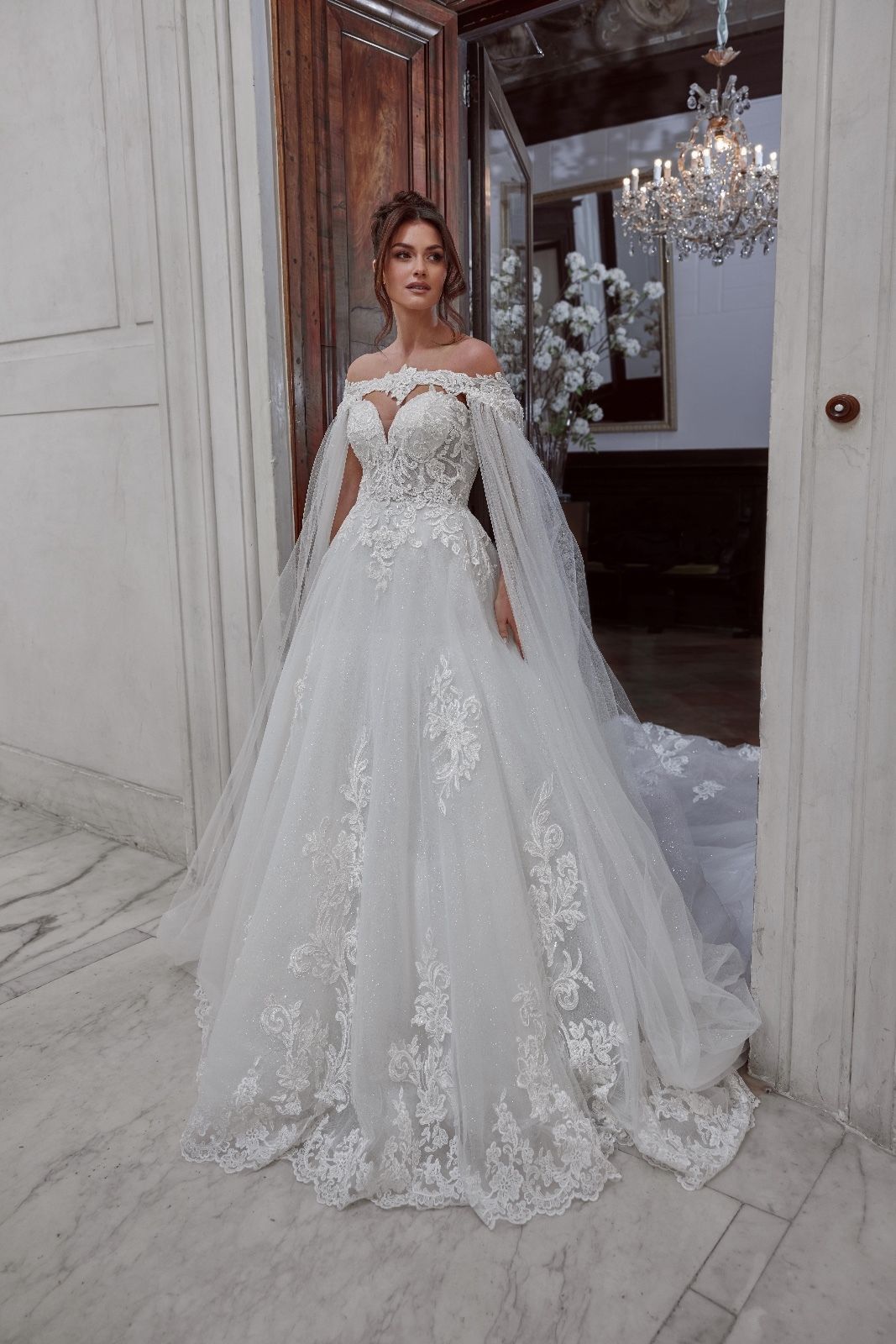 Una donna in abito da sposa bianco è in piedi davanti a una porta.