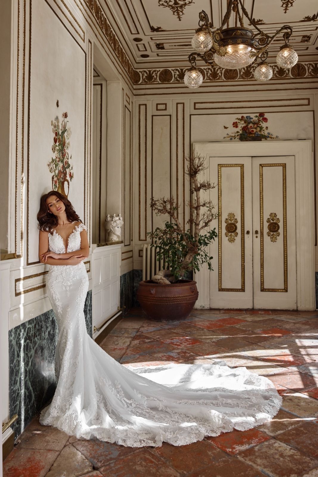 Una donna in abito da sposa è appoggiata a un muro in un corridoio.