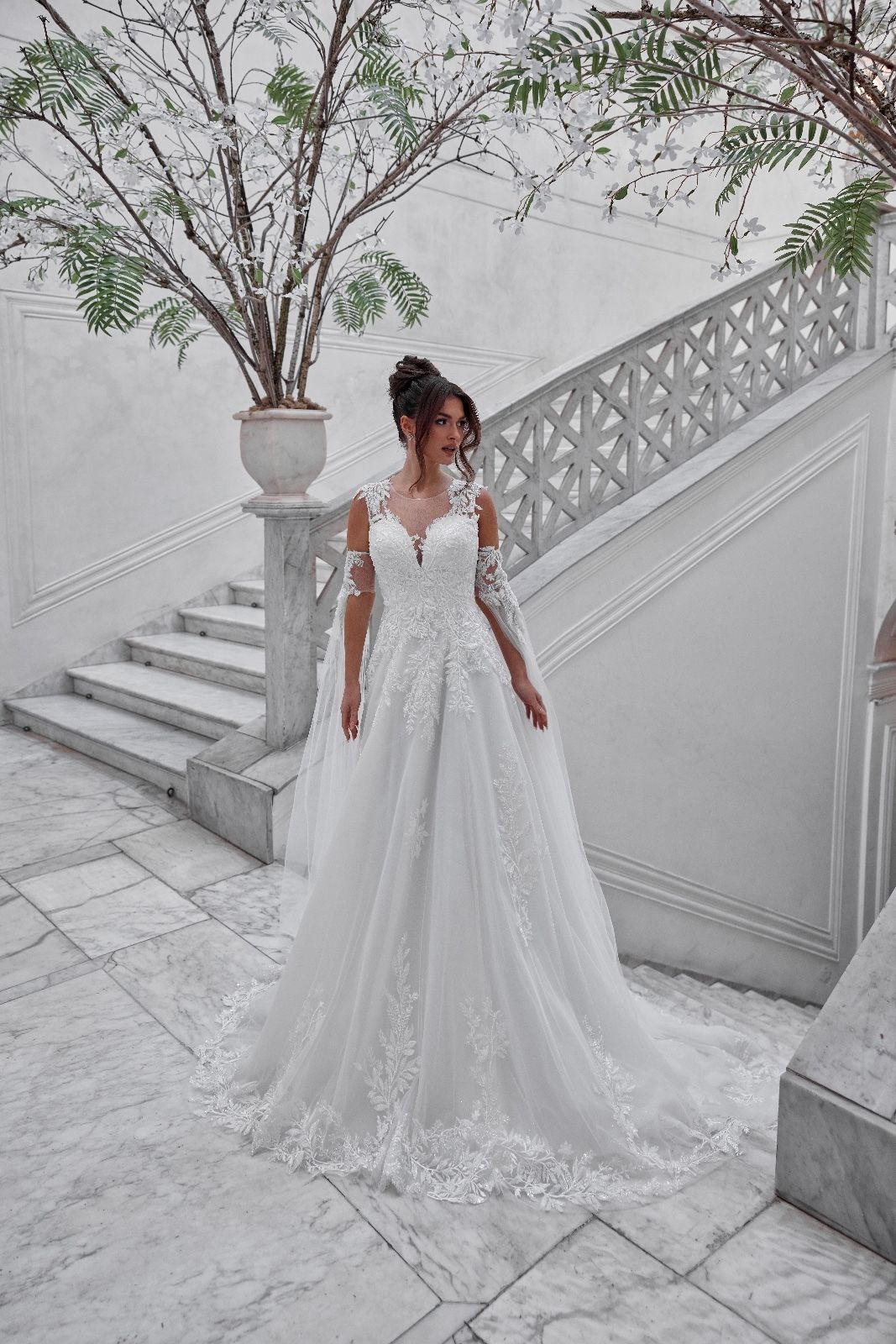 Una donna con un abito da sposa bianco è in piedi accanto alle scale.