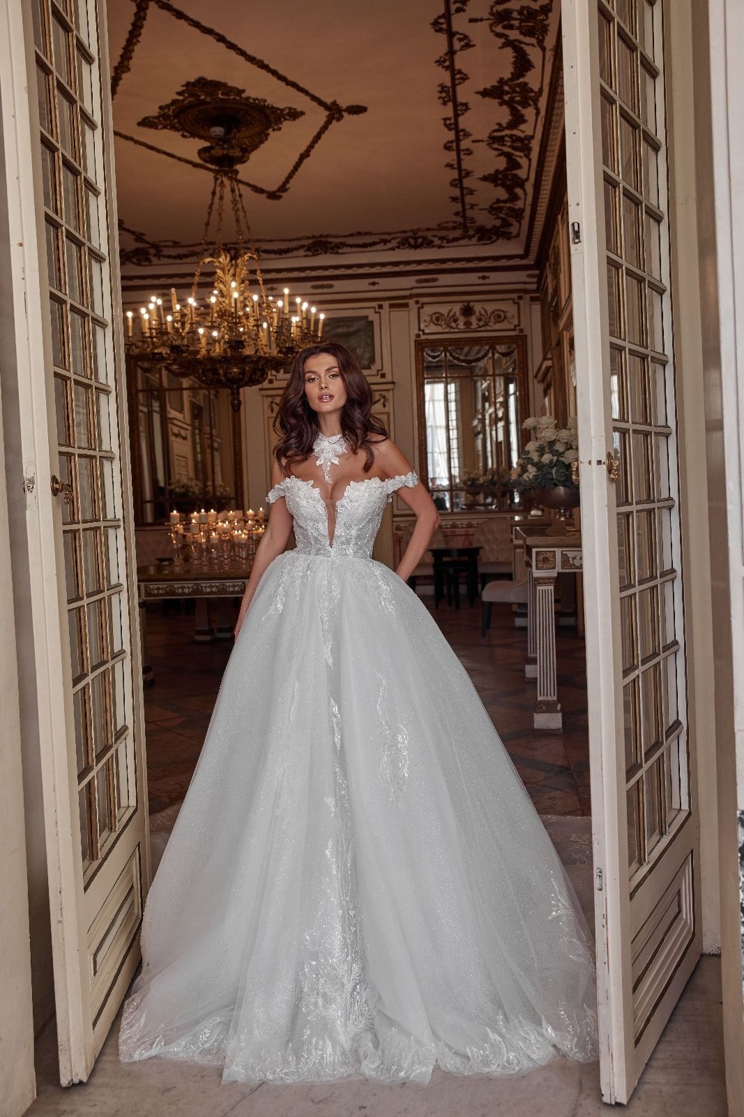 Una donna in abito da ballo bianco è in piedi davanti a una porta in una stanza.