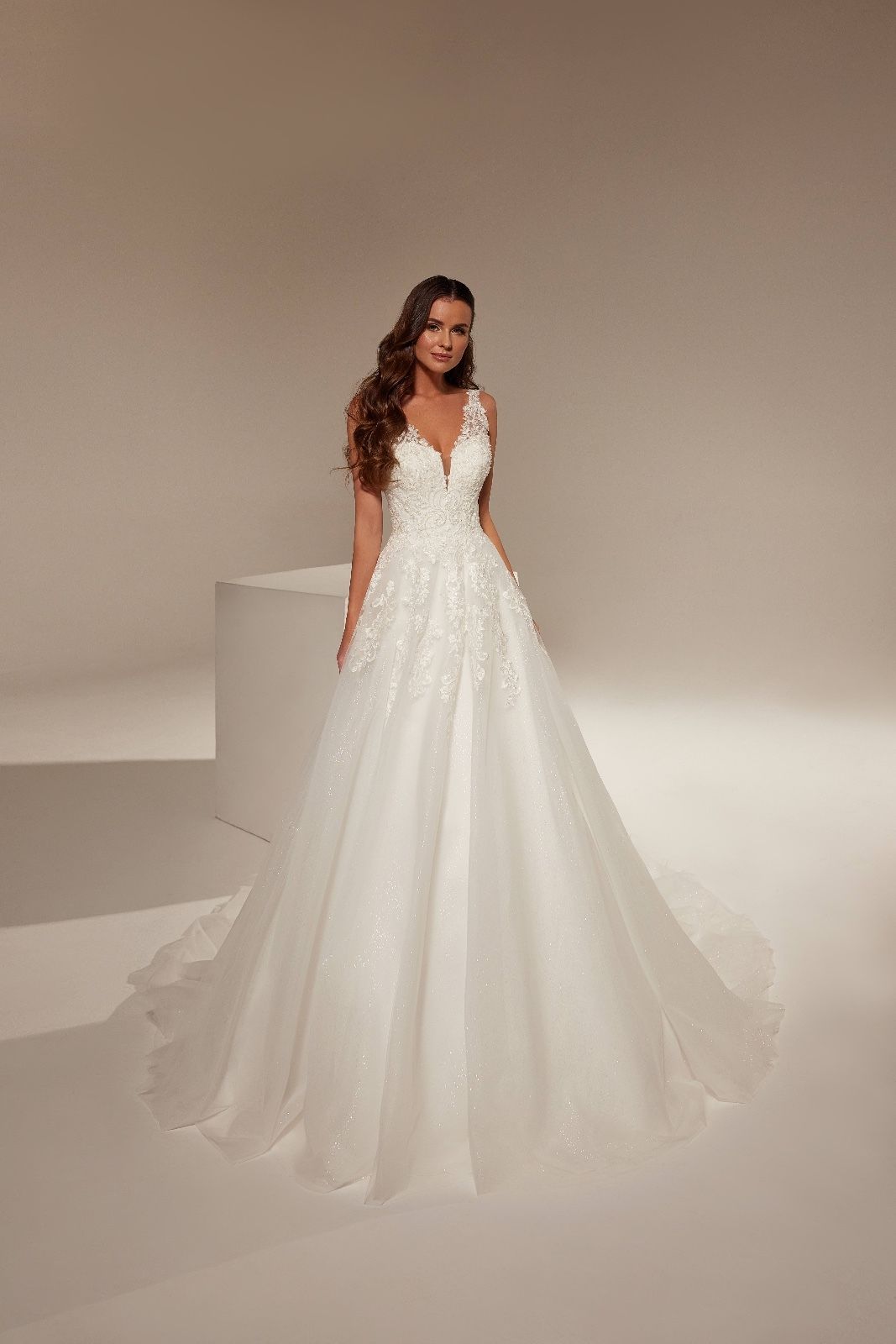 Una donna con un abito da sposa bianco è in piedi accanto a un cubo bianco.