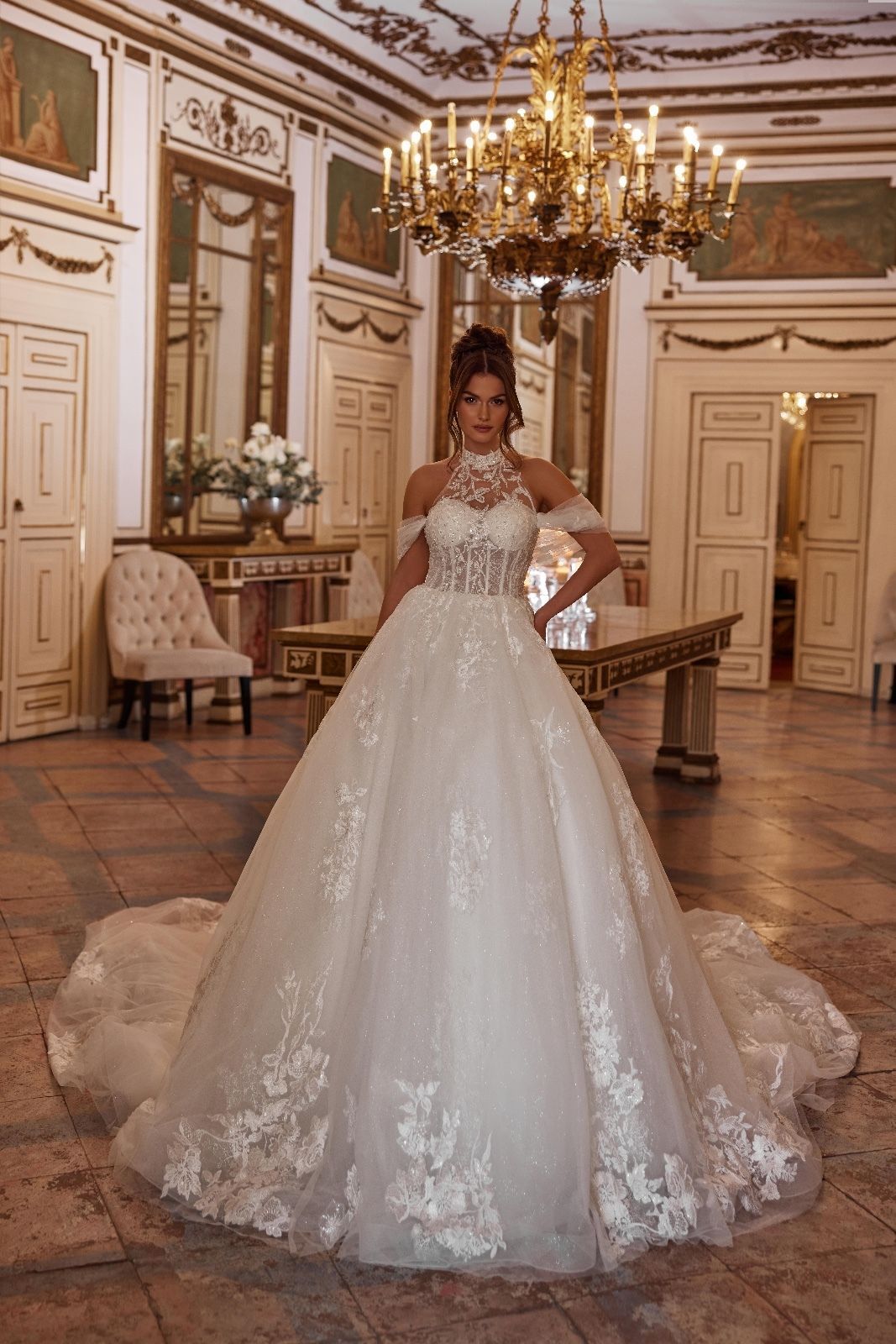 Una donna in abito da sposa è in piedi in una stanza con un lampadario.