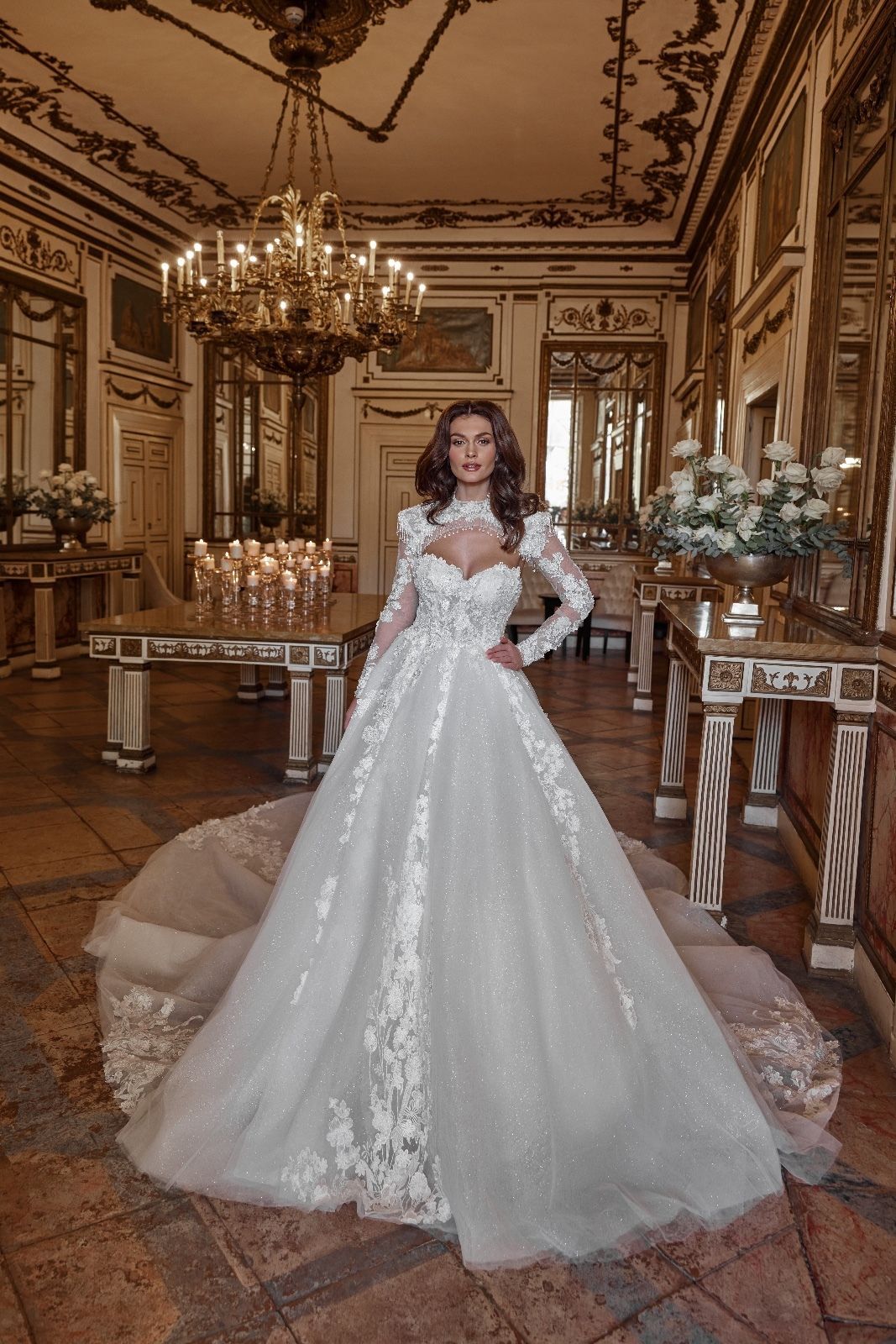 Una donna in abito da sposa è in piedi in una stanza con un lampadario.