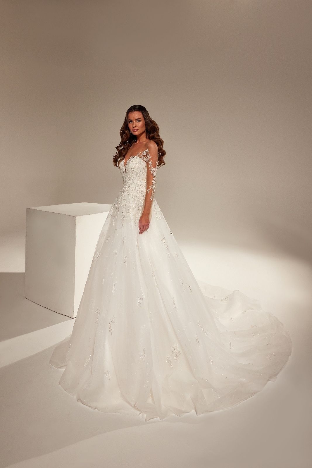 Una donna con un abito da sposa bianco è in piedi accanto a un cubo bianco.