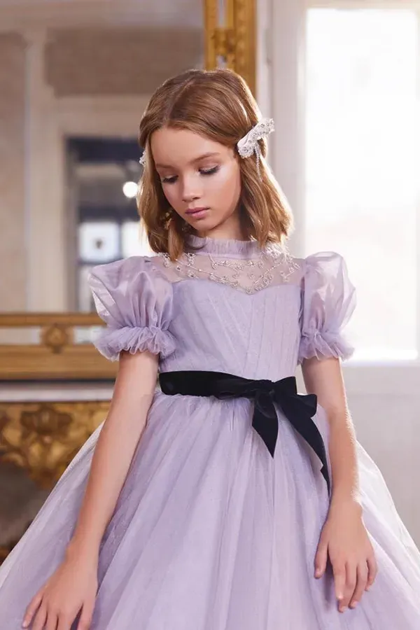 Una bambina con un vestito viola è in piedi davanti allo specchio.