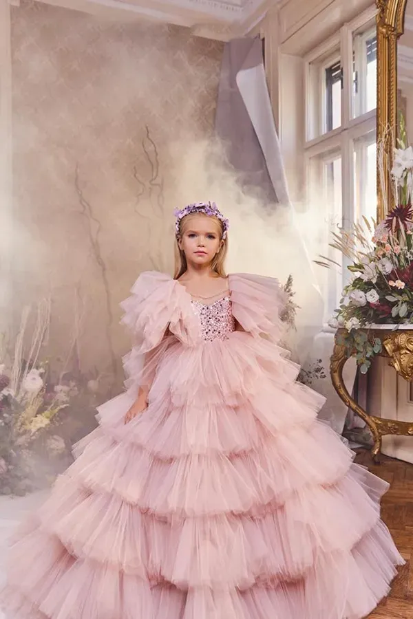 Una bambina indossa un vestito rosa e una corona.