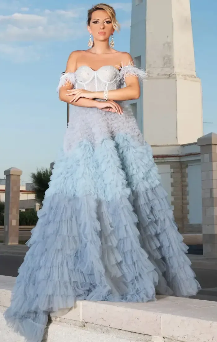 Una donna con un lungo vestito blu è in piedi sulle scale