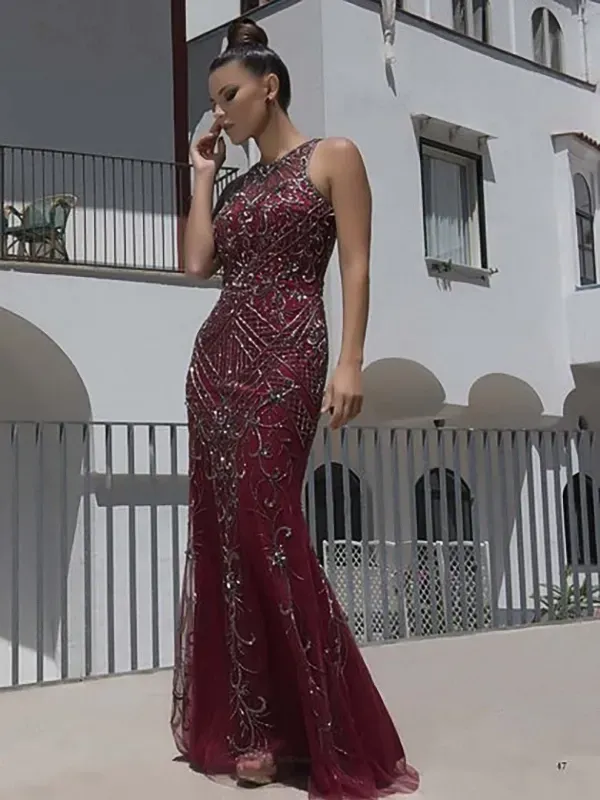 Una donna con un lungo vestito rosso è in piedi davanti a un edificio bianco