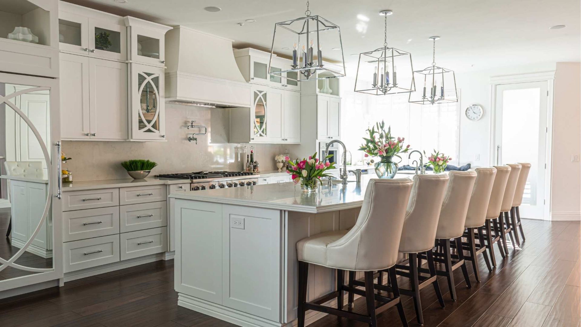 a modern, clean, white kitchen with wooden floors and an island countertop with comfortable seating