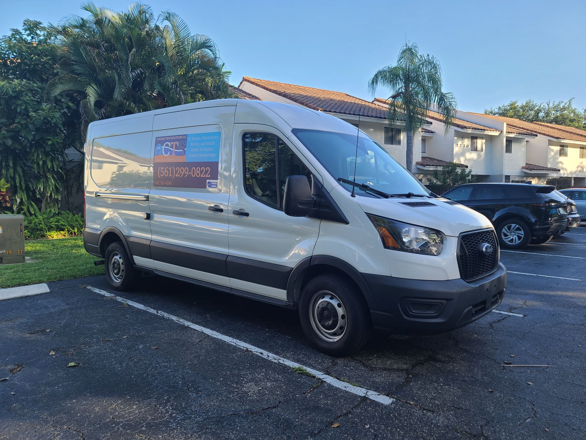 A family is sitting on a couch under an air conditioner in a living room.
