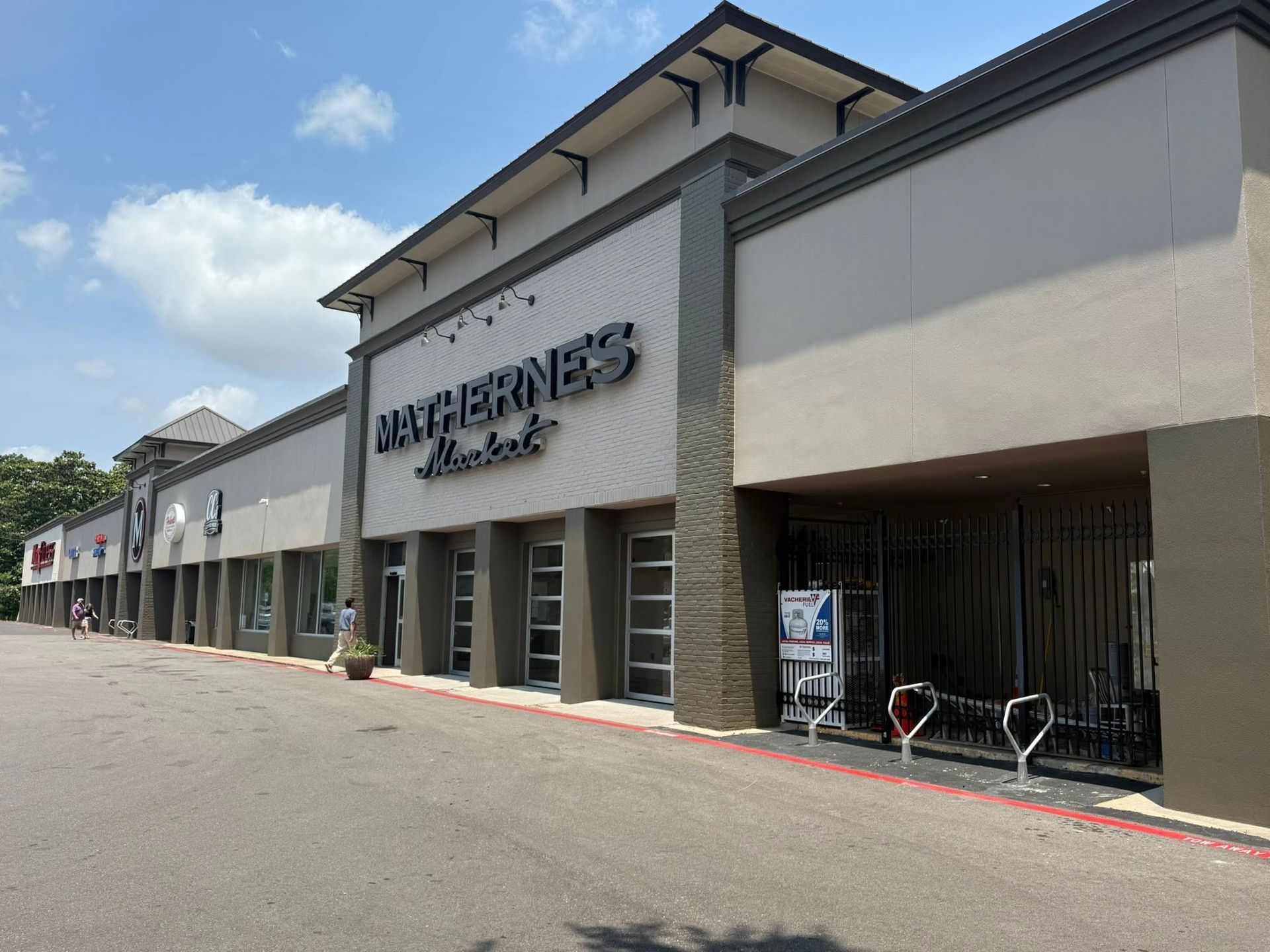 Exterior of a Walmart storefront in a strip mall under a bright blue sky