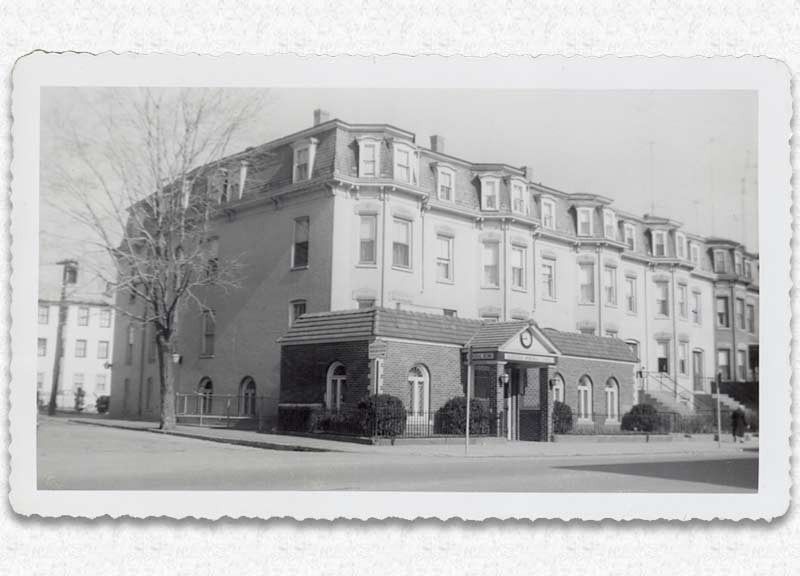 Large multi-story brick building with dormer windows, likely a school or institutional building.