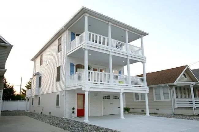 A white house with many balconies and a red door