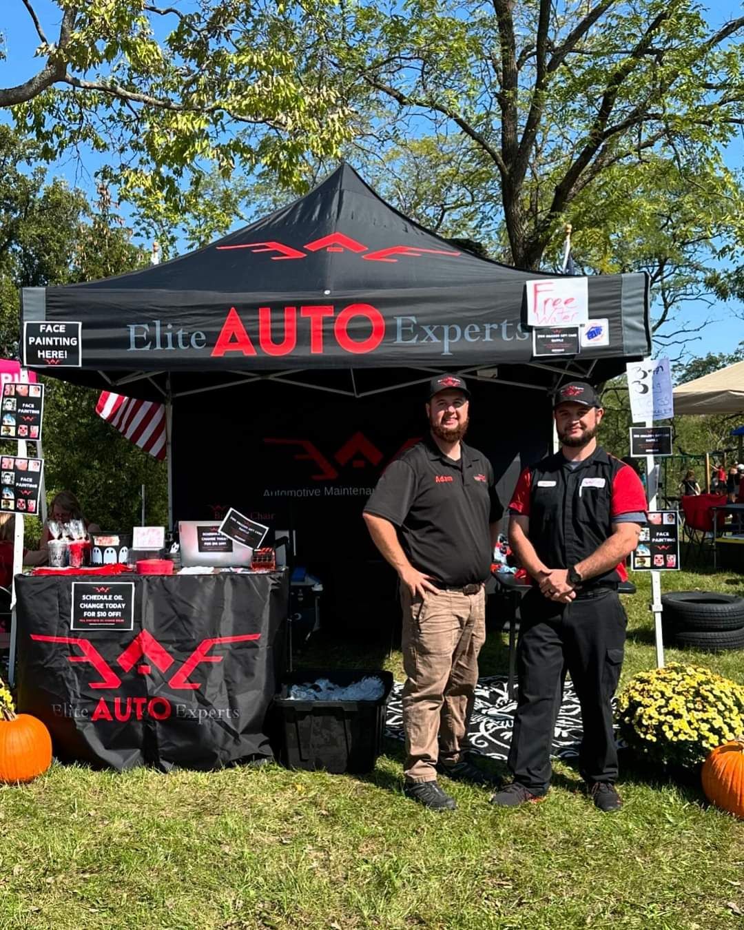 Two men are standing in front of a tent at a car show.