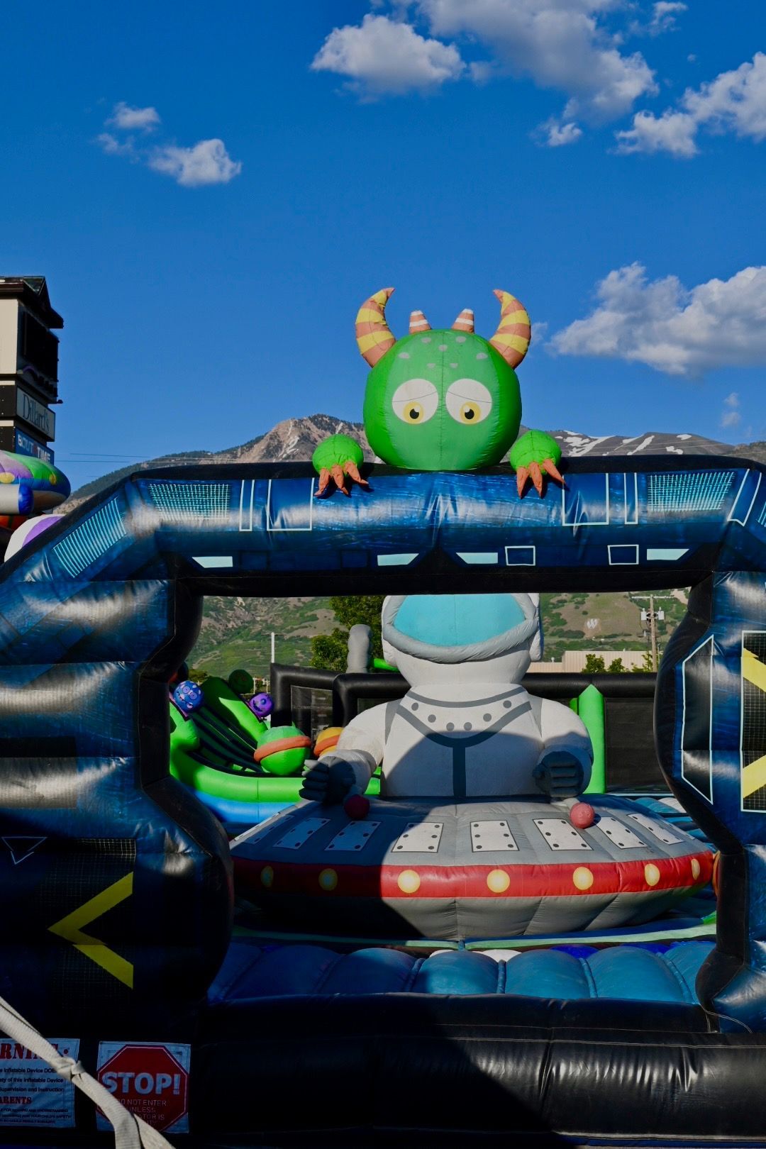 A green monster is sitting on top of an inflatable space ship.