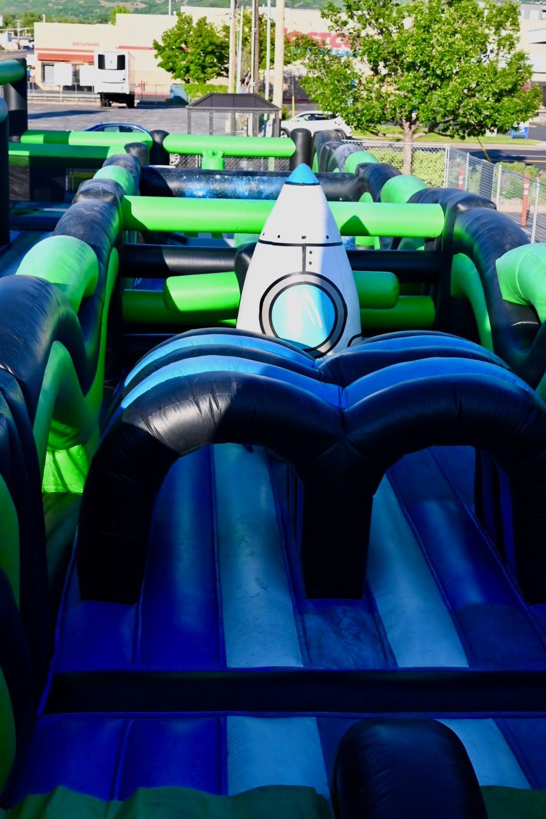 A green and blue inflatable obstacle course with a rocket in the middle