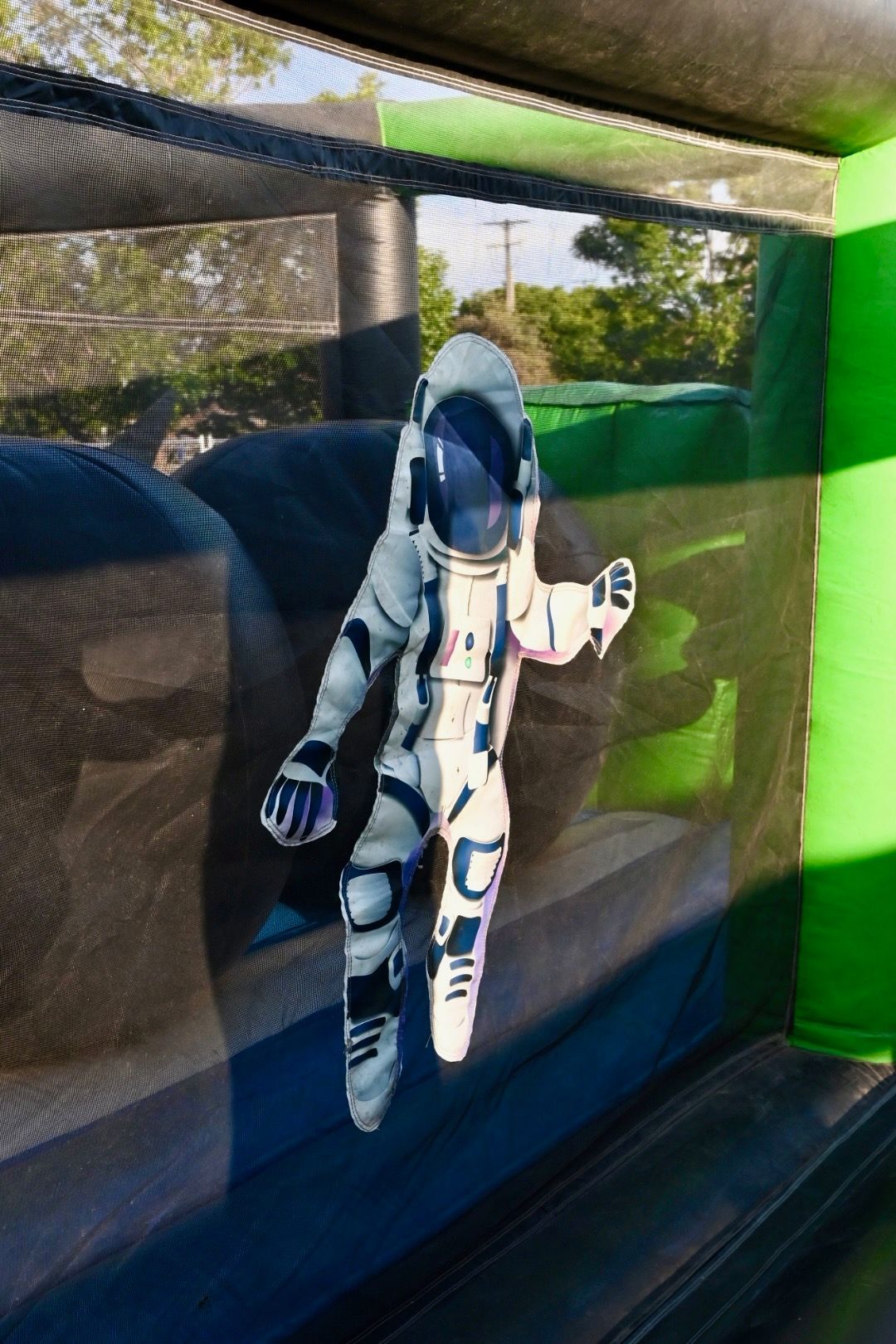 An astronaut is flying through the air in a bouncy house.