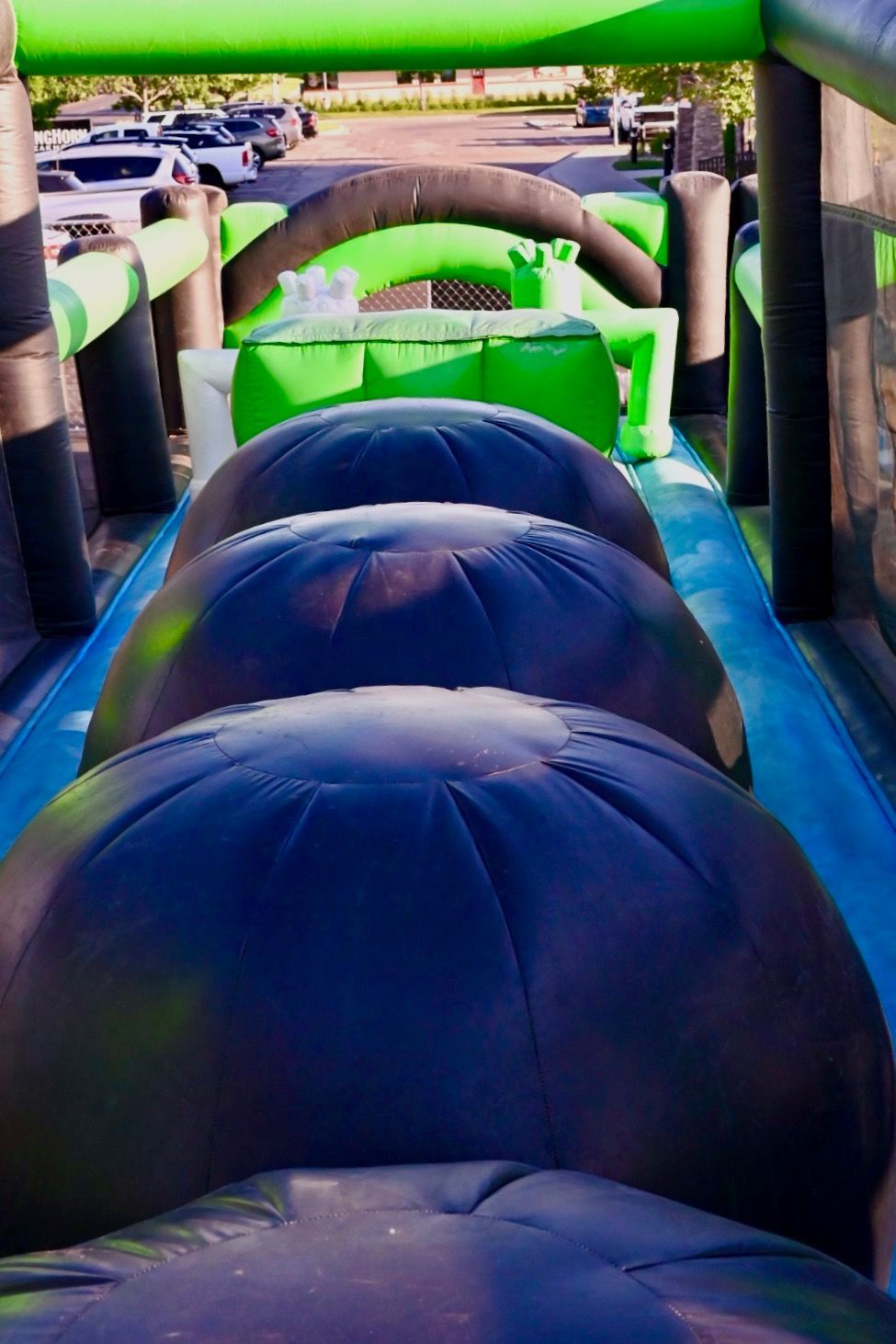 A row of black and green inflatable balls are lined up on top of each other on an inflatable obstacle course.