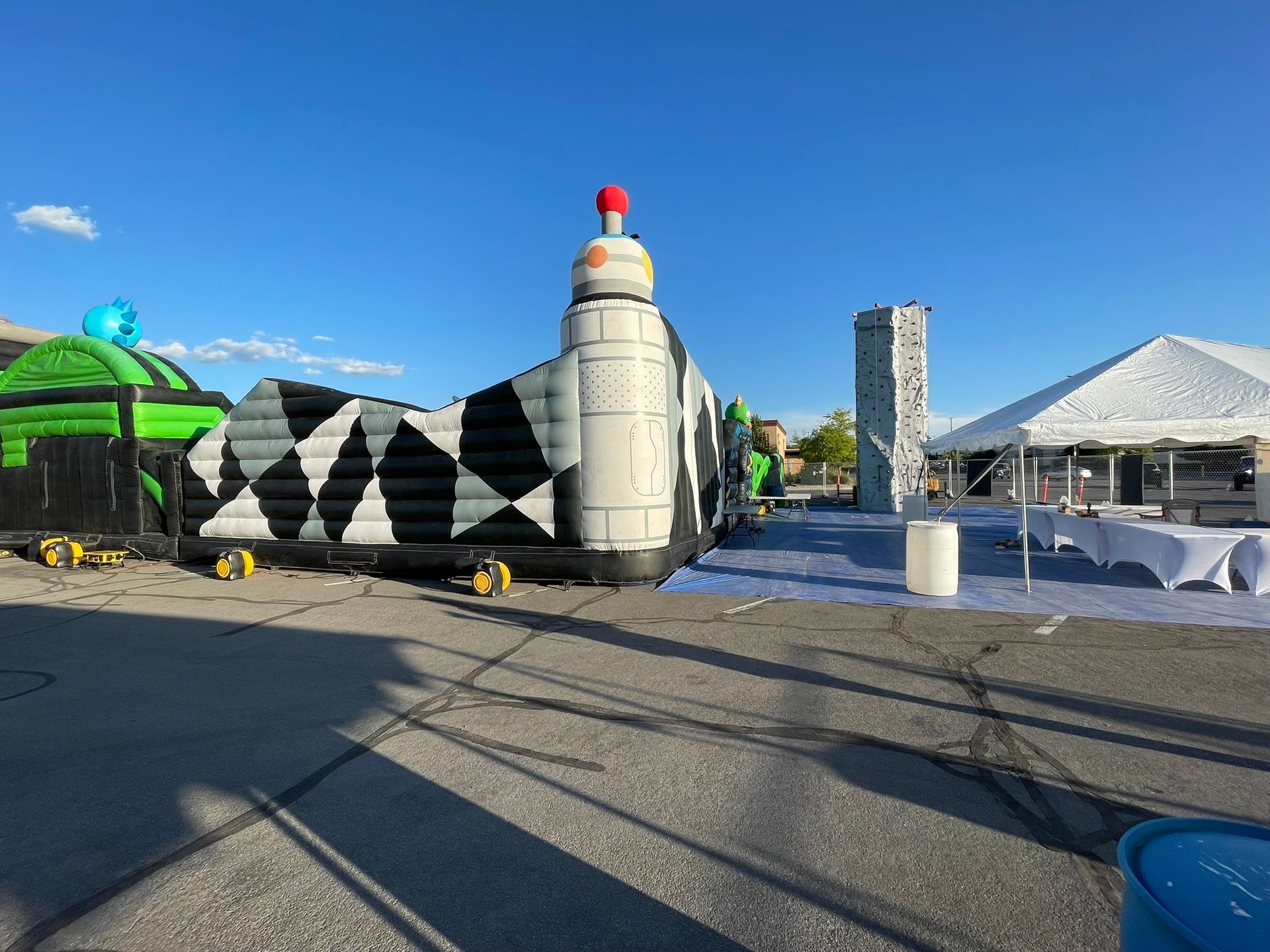A large inflatable castle is sitting in a parking lot next to a tent.