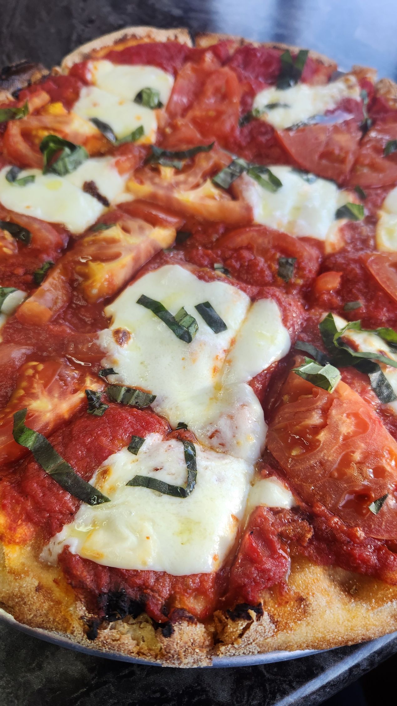 Pizza with red sauce, white mozzarella, fresh basil, on a crispy crust.