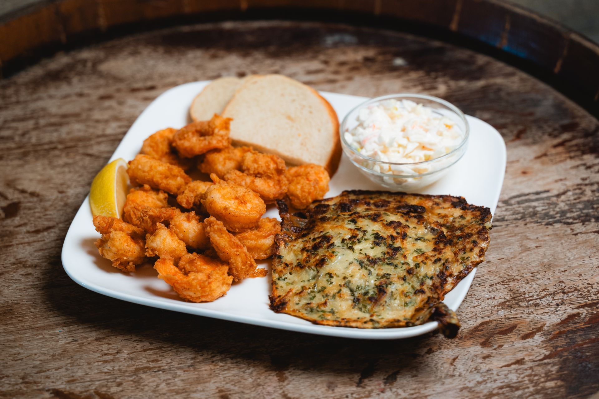 Fried shrimp, bread, coleslaw, and a side of garlic bread on a white plate.