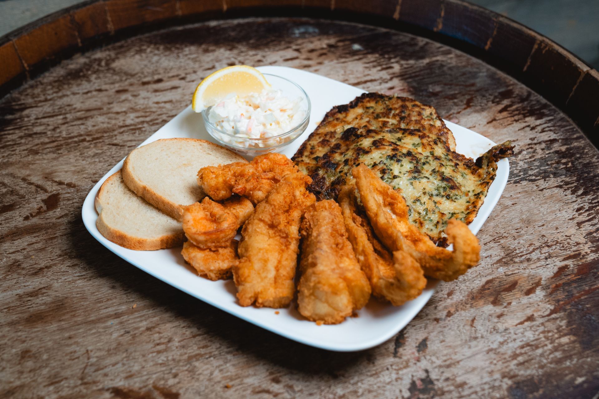 Plate of fried fish with bread, coleslaw, and a lemon wedge.