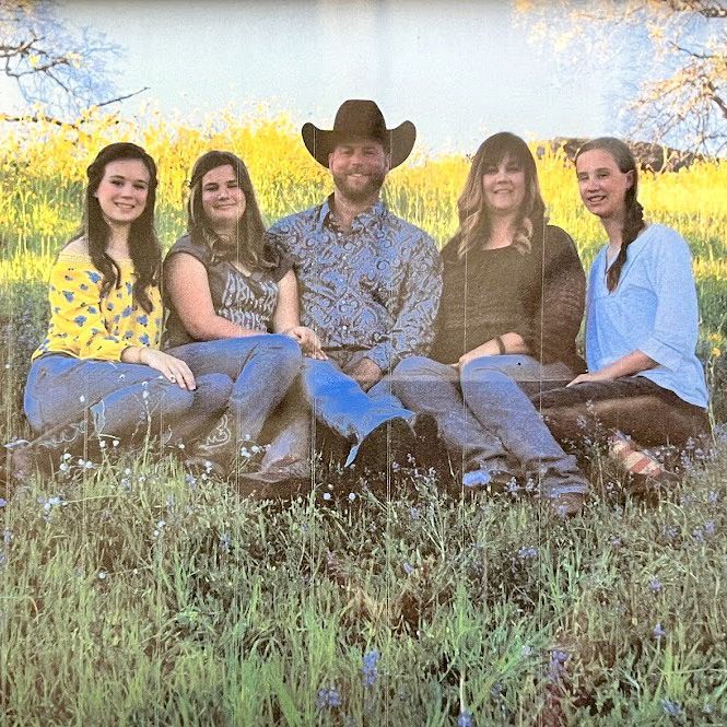A family is posing for a picture in a field of tall grass.