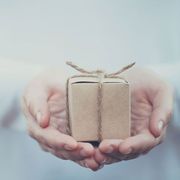 A person is holding a small cardboard box with a string tied around it
