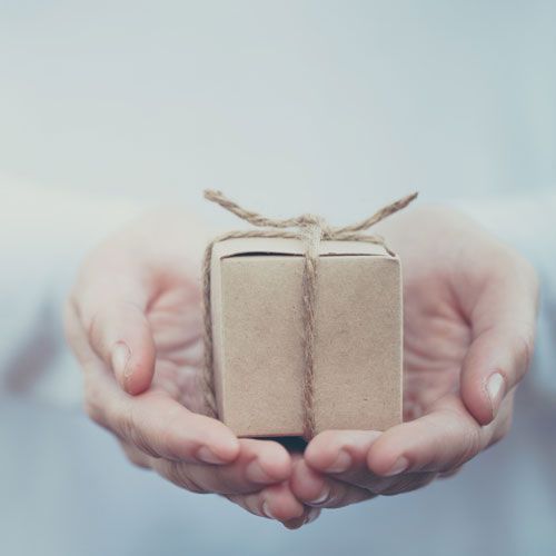 A person is holding a small cardboard box with a string tied around it