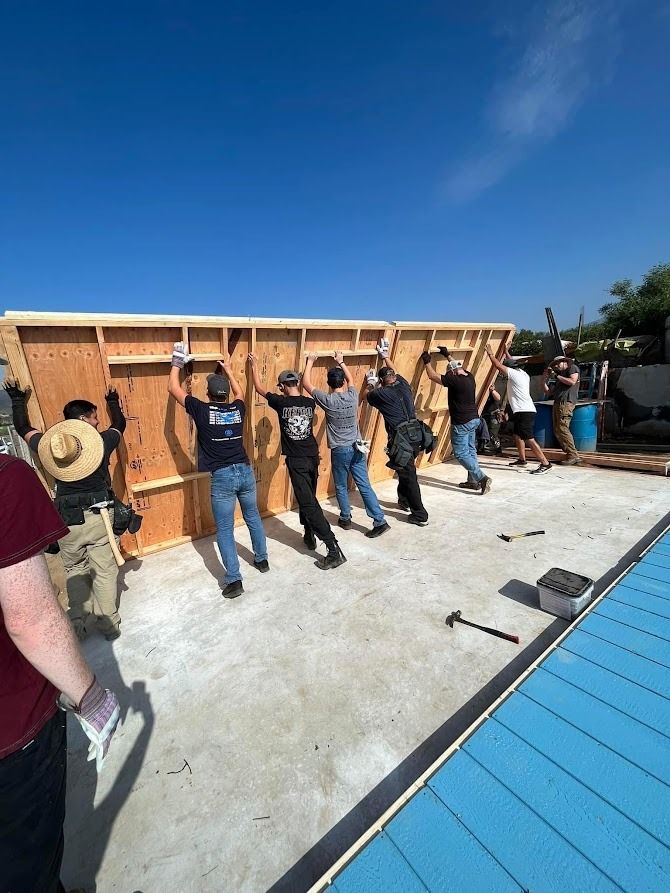 A group of people are working on a wooden wall.