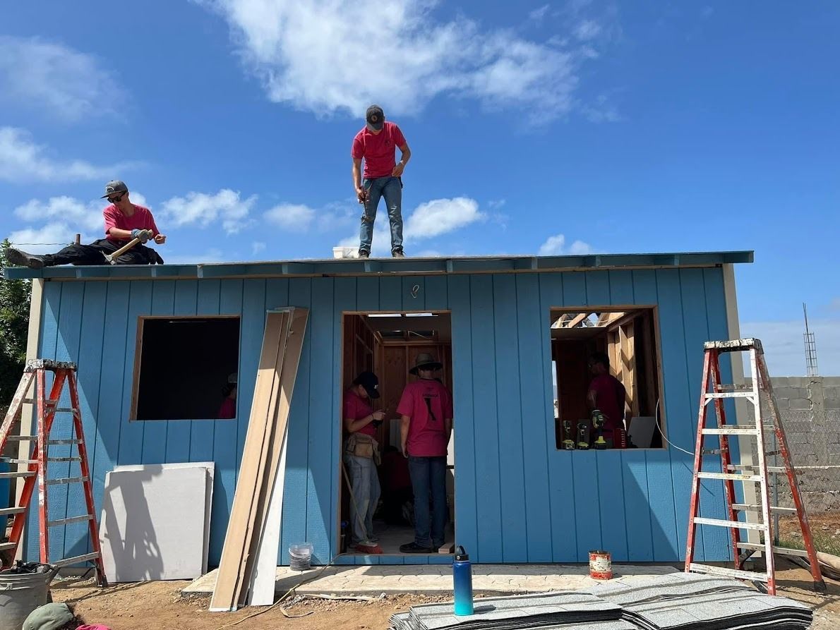 A group of people are working on a blue house.