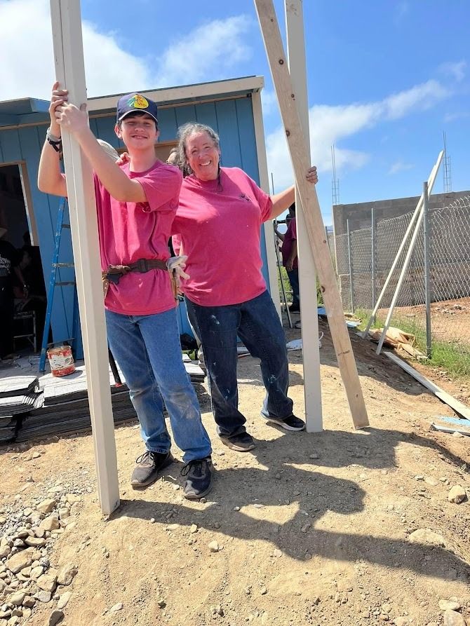 A man and a woman are standing next to each other holding wooden poles.