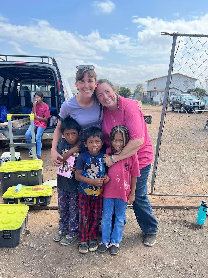 Two women are posing for a picture with three children in a field.