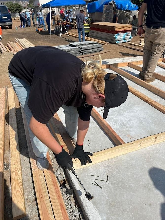 A woman is working on a wooden structure on a construction site.