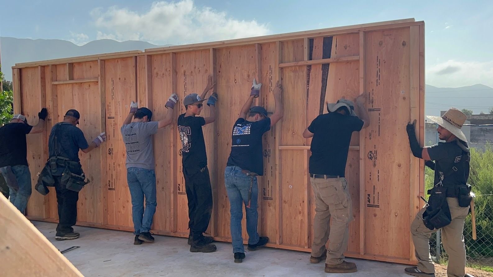 A group of construction workers are working on a wooden wall.