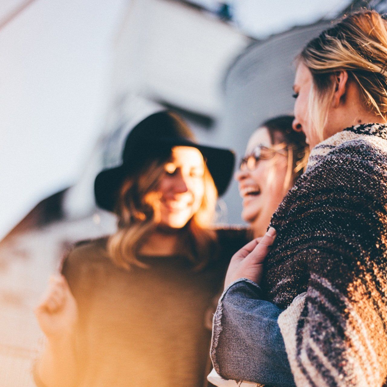 A woman in a hat is talking to two other women
