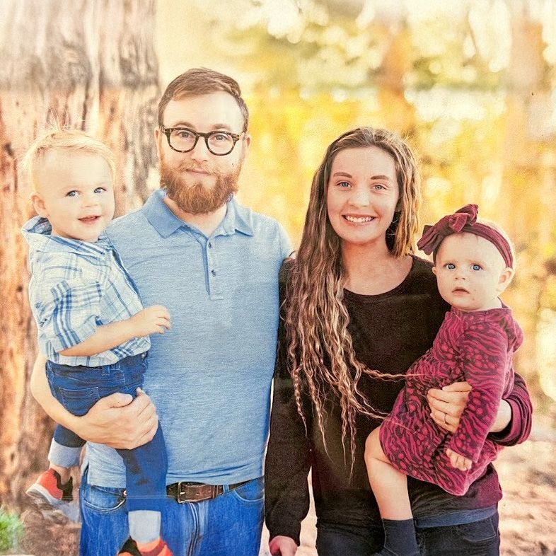 A man , woman , and two children are posing for a picture.