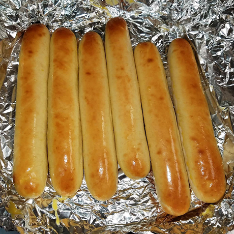 A bunch of golden brown breadsticks sitting on a piece of tin foil