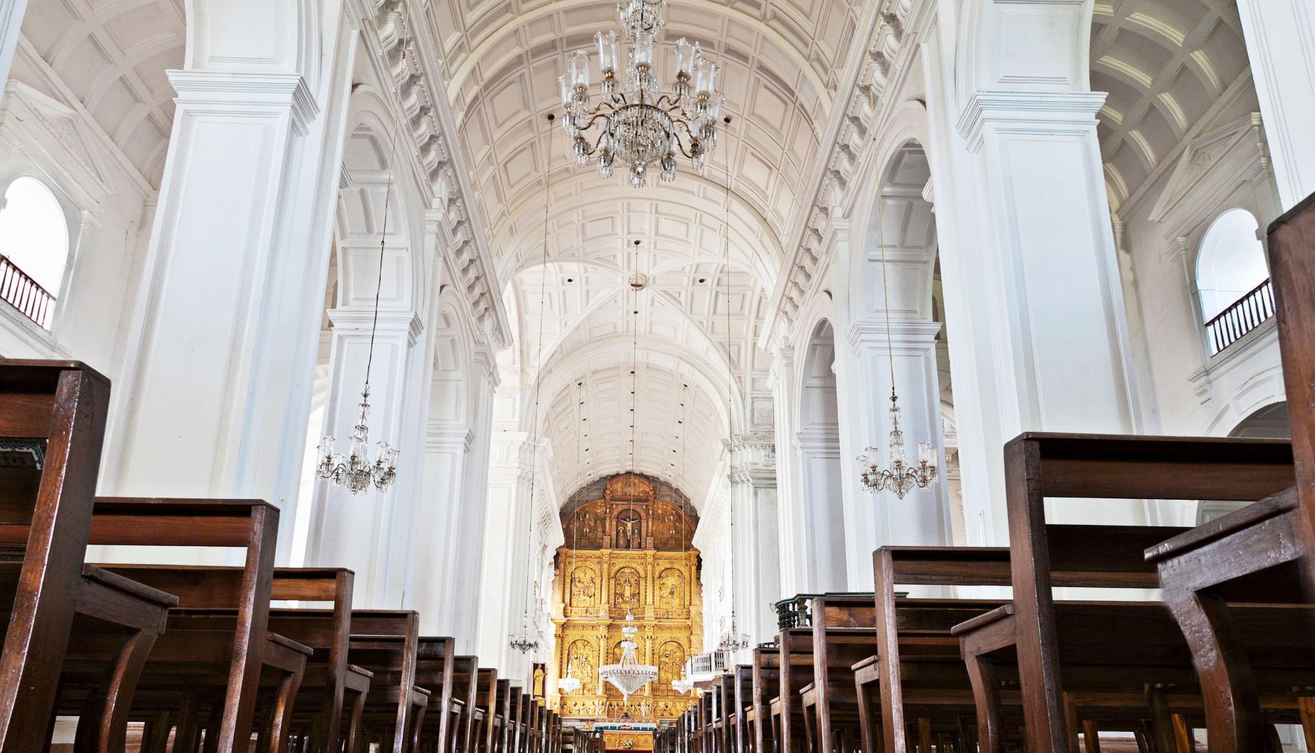 Family celebrating a birthday: grandparents with party hats, cake, being kissed, two adult children watching.