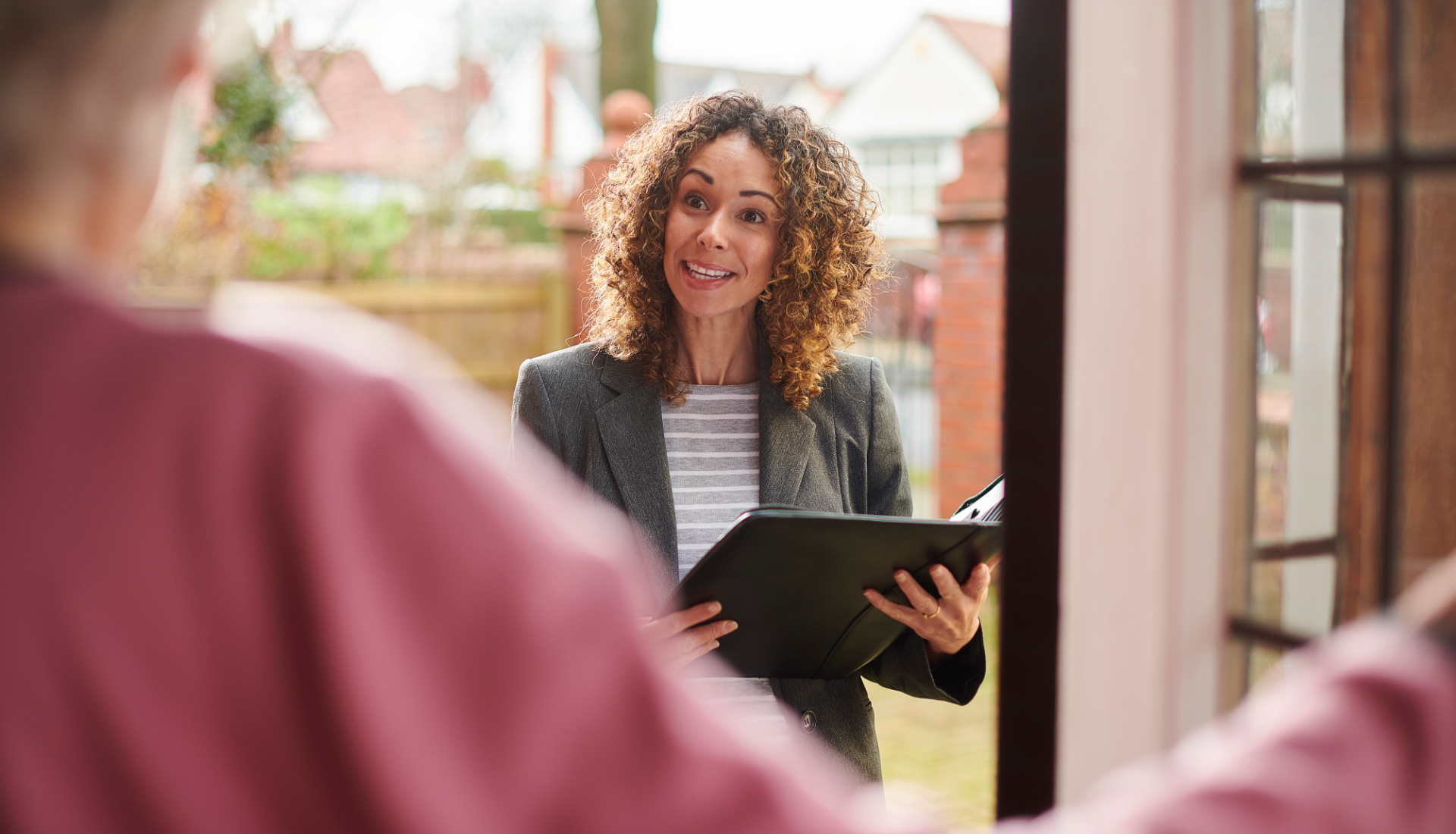 Family outdoors, smiling and talking; man gesturing, elderly man sitting, young girl, and blonde women.