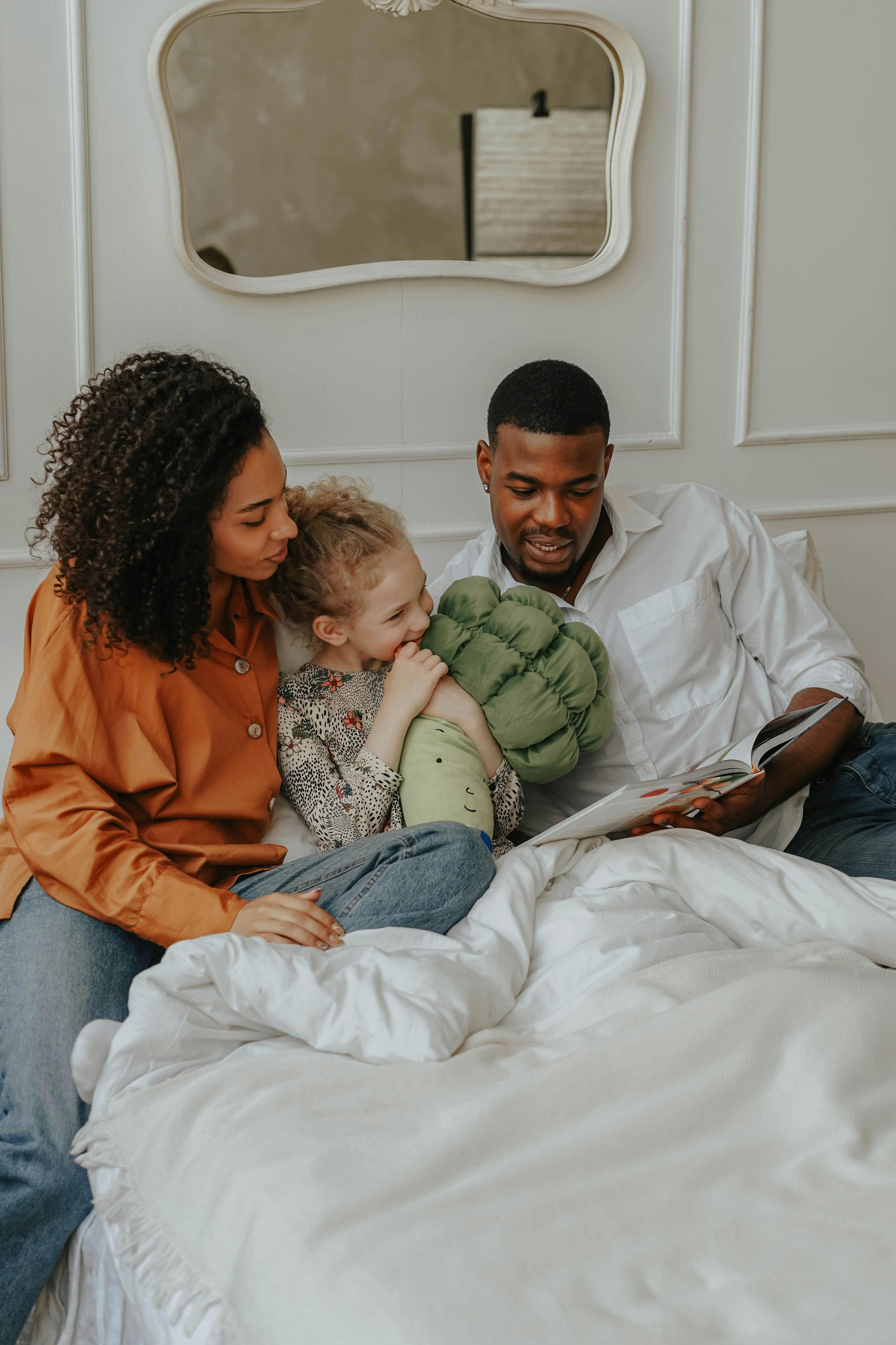Smiling couple under a yellow and white umbrella, outdoors in a garden setting.