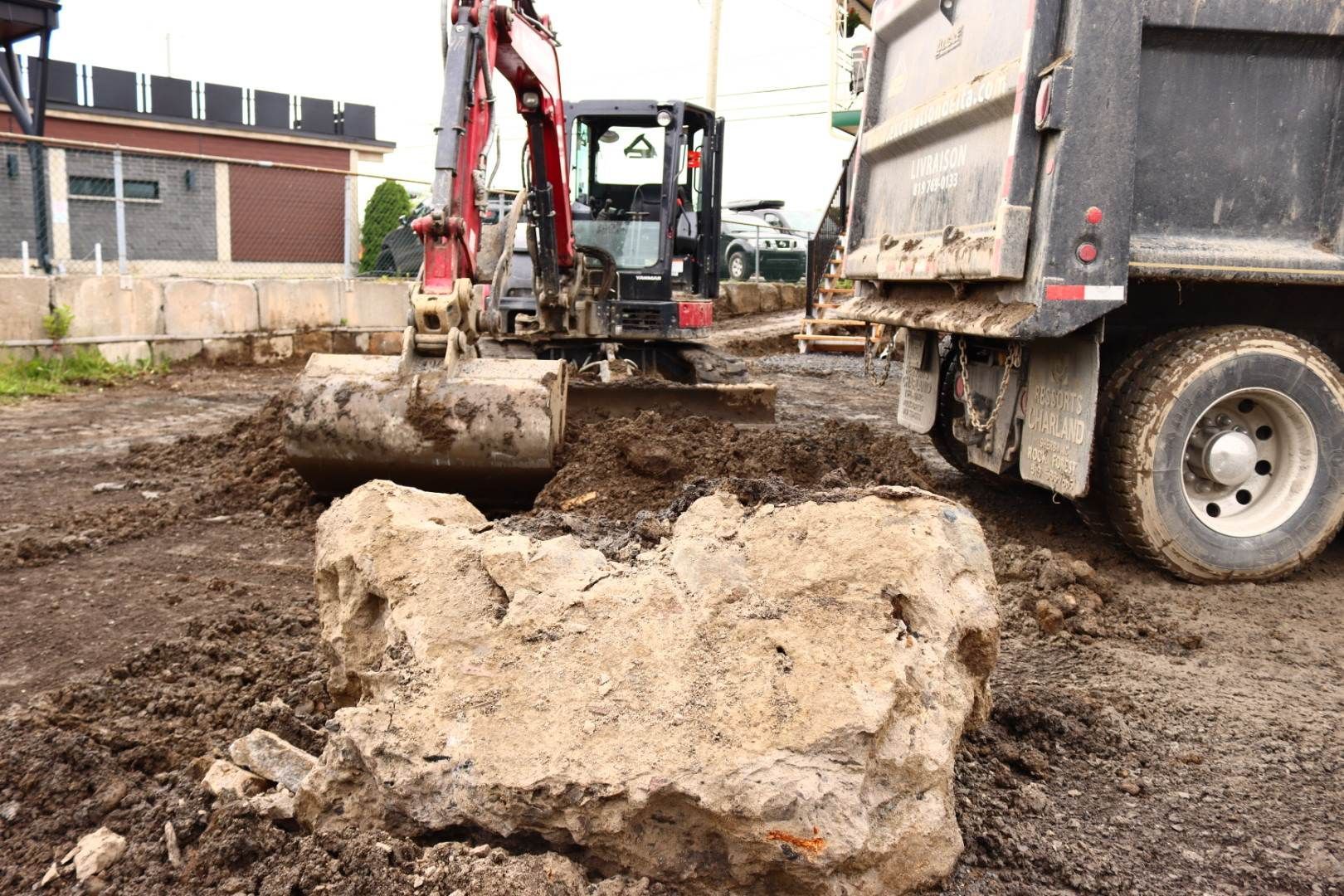 Une excavatrice creuse un trou dans le sol à côté d'un camion-benne.