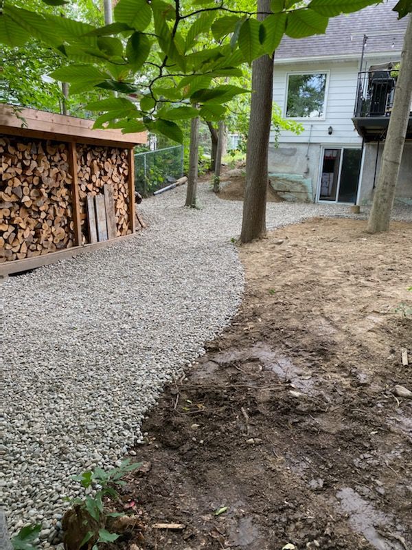 Il y a un tas de bois dans la cour à côté d'une maison.