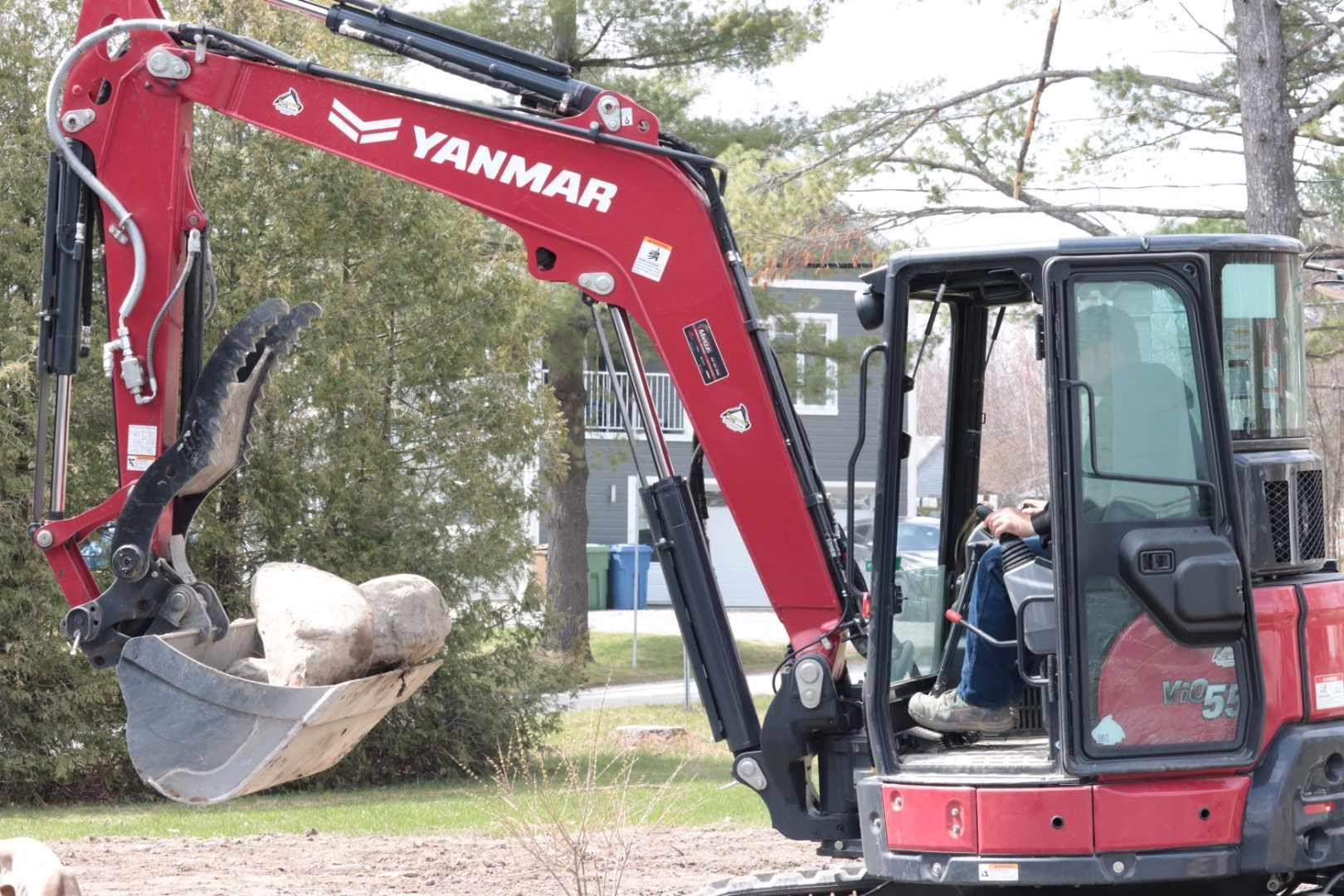 Une excavatrice Yanmar rouge et noire est assise dans une cour.