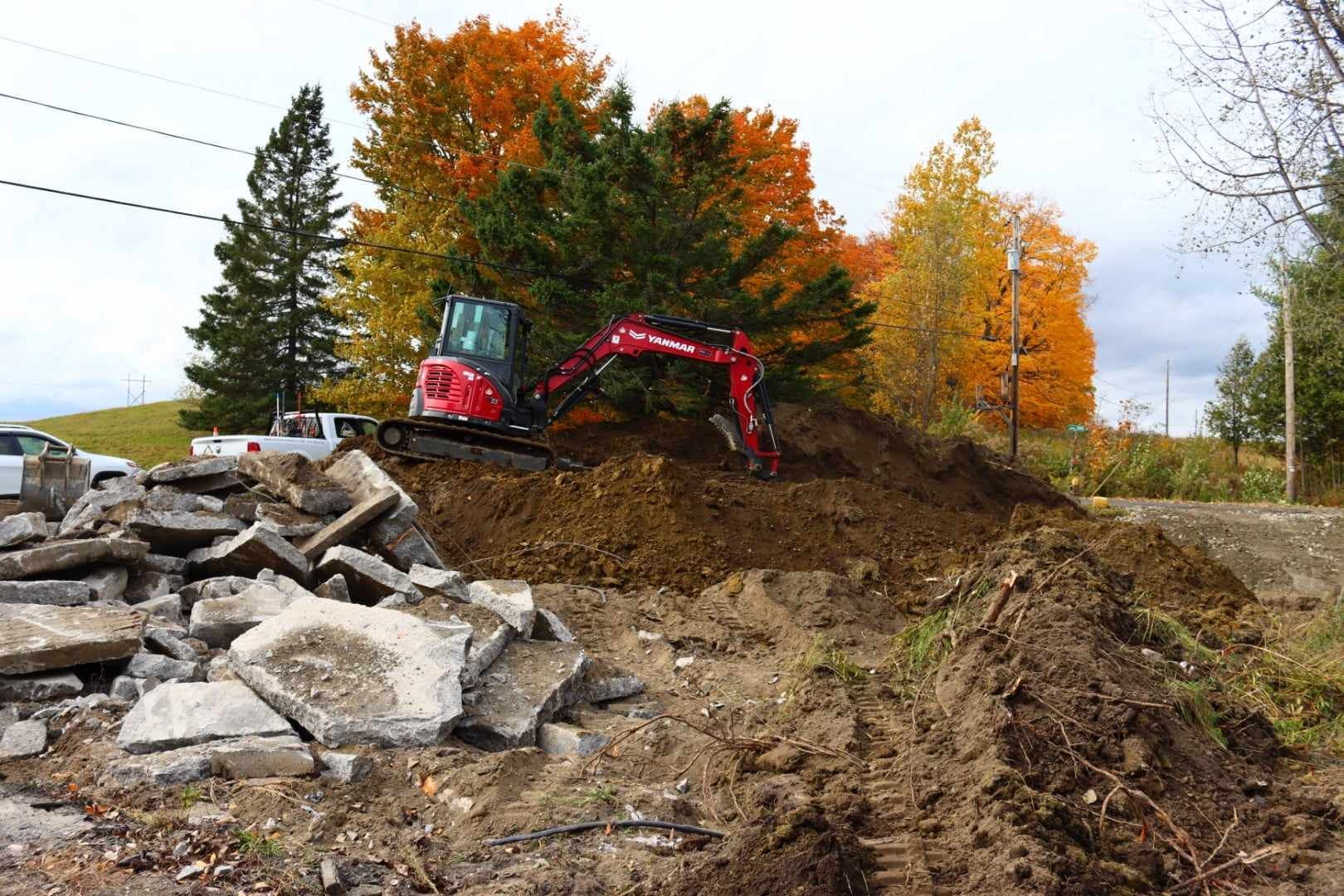 Une excavatrice rouge creuse dans un tas de terre.