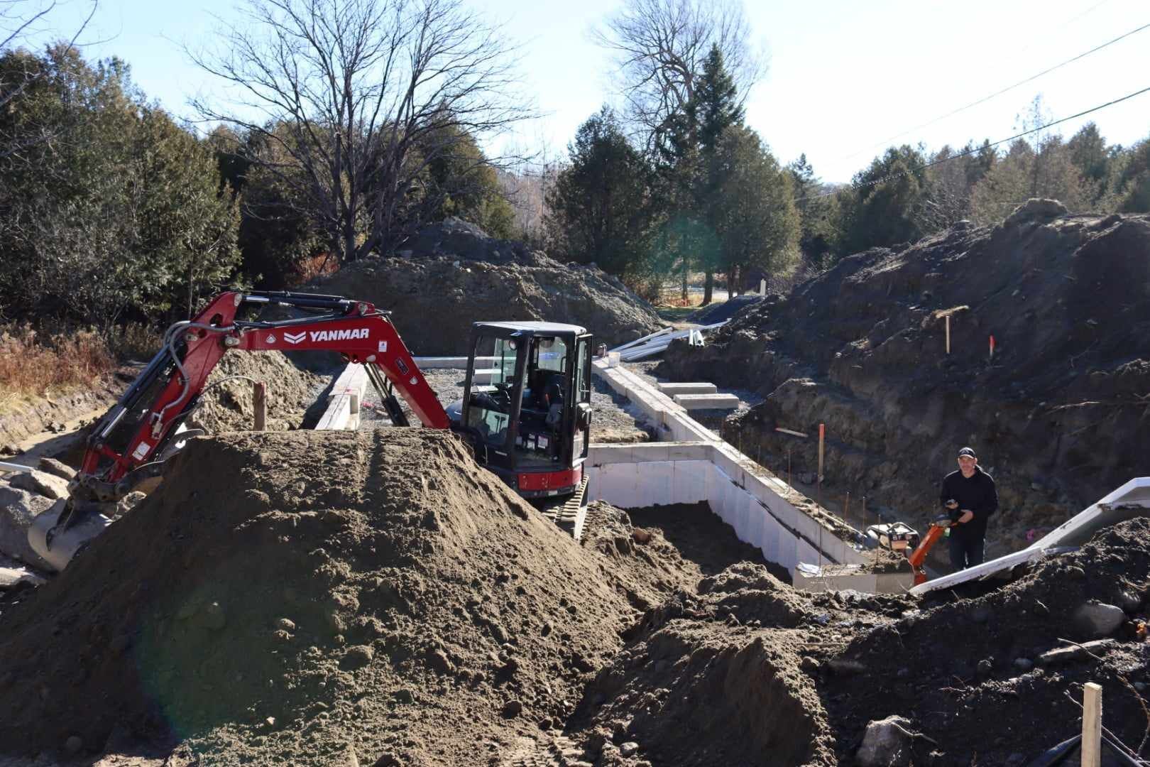 Une excavatrice rouge creuse un trou dans la terre